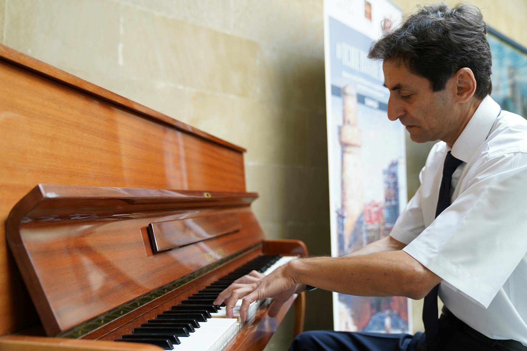 A man intensely playing a piano indoors in Bakı, Azerbaijan.